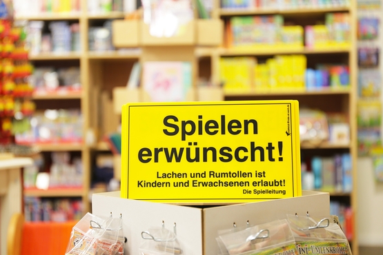 Auf einem Gelben Warnschild steht: Spielen erwünscht! Lachen und Rumtollen ist Kindern und Erwachsenen erlaubt!