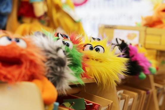 Eine reihe bunter, flauschiger, Monster-Handpuppen.